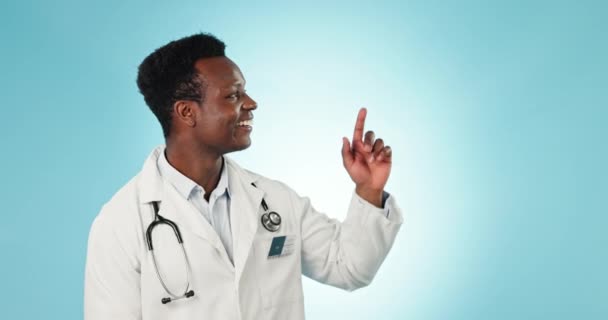 Face, pointing or doctor with space, black man or healthcare on a blue studio background. Portrait, African person or medical professional with advertising, decision or opportunity with information. - Footage, Video