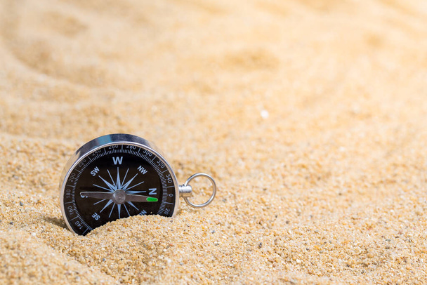 Kompas w piasku morskim na tle plaży z miejscem do kopiowania dla dodawania wiadomości tekstowych lub korzystania z komponentów do projektowania. Cel podróży letnich i Koncepcja nawigacji w tle. - Zdjęcie, obraz