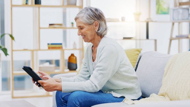 Relax, tablet and senior woman on sofa in living room scroll on social media, mobile app or the internet. Rest, online and elderly female person browsing on website with technology in lounge at home - Foto, Bild