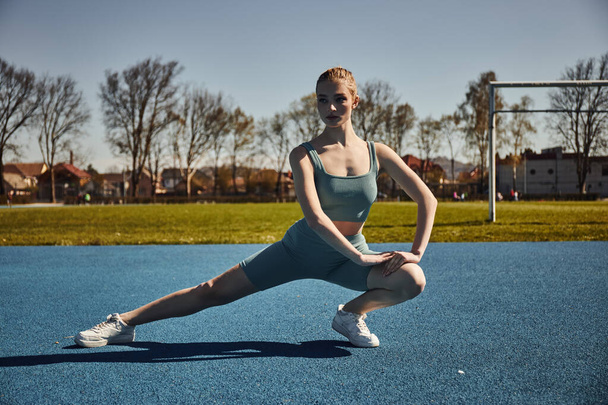 приваблива спортсменка з хвіст вправами в активному одязі на відкритому повітрі, жінка робить легені - Фото, зображення