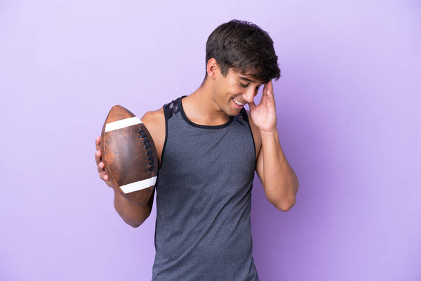 Junger Mann spielt Rugby isoliert auf violettem Hintergrund und lacht - Foto, Bild