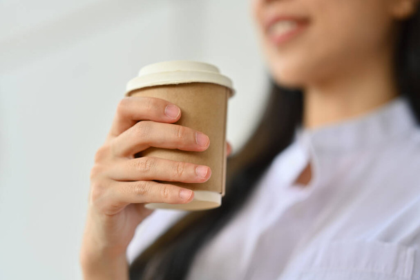 Select focus on businesswoman hand holding disposable paper coffee cup, relaxing during break. - Photo, Image