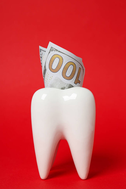 Dekoracyjny ząb i pieniądze na czerwonym tle - Zdjęcie, obraz
