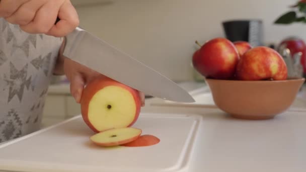 リンゴをスライスしてさらに乾燥させます. キッチンナイフを使用した女性の手は,ベーキングシートに広がるスライスに大きな熟したリンゴを切りました - 映像、動画