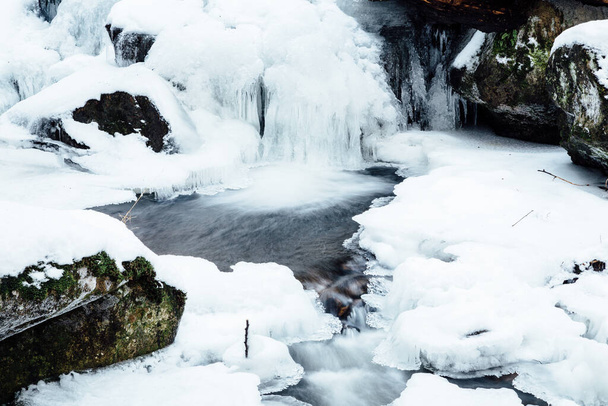 jäädytetty vesiputous talvimetsässä
 - Valokuva, kuva