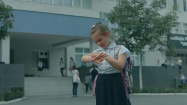 Menina bonita escola caucasiana usando smartwatch ao ar livre no parque escolar. Criança feliz conversando com seu pai em videochamada no smartphone. Relógio de pulso inteligente com rastreador GPS - Filmagem, Vídeo
