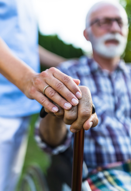 Primo piano della mano dell'uomo anziano sul bastone da passeggio con la mano dell'infermiera femminile come supporto ed empatia - Foto, immagini
