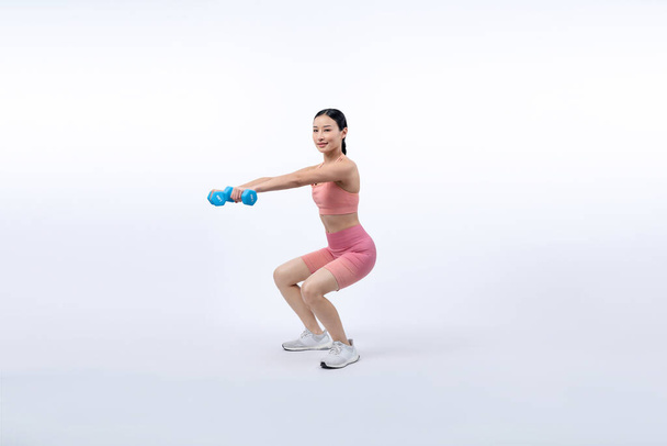 Energiczna kobieta wykonująca ćwiczenia podnoszenia hantli na odosobnionym tle. Młoda atletyczna azjatycka kobieta siła i wytrzymałość sesji treningowej jako rutyna treningu ciała. - Zdjęcie, obraz
