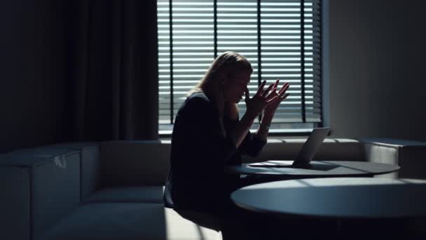 Втомлена біла ділова жінка тримає руки на голові через вигорання після роботи на бездротовому ноутбуці в темному офісі. Жінка-підприємець може контролювати емоції і обробляти стрес під час робочих проблем. - Кадри, відео