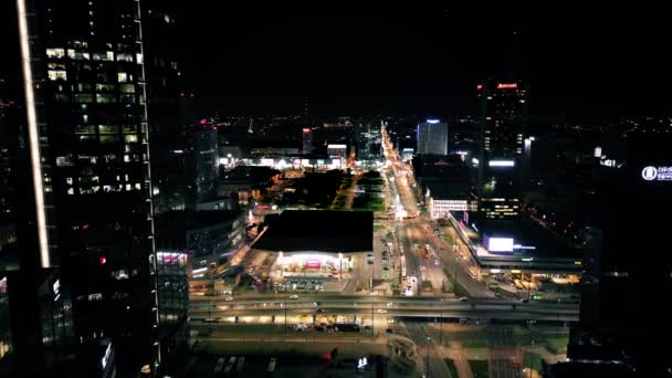 antenni näkymä drone Varsovan kaupungin keskustan liikealueella yöllä, lentää yli modernin keskustan pääaukiolla, pilvenpiirtäjiä valaistu kaduilla - Materiaali, video
