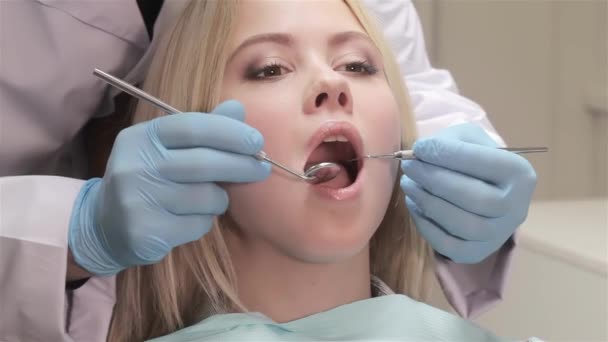 Dentysta bada pacjentowi przez sondę dentystycznych. Kaukaski kobieta odbiera sprawdzanie u dentysty. Bliska blondy kobiety szeroko otwarte usta do badania stomatologiczne - Materiał filmowy, wideo