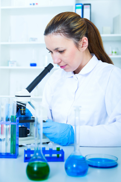 Woman working with a microscope in a lab - Zdjęcie, obraz