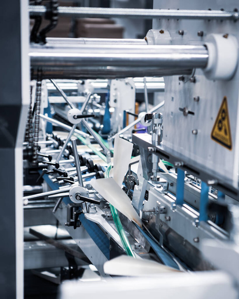 Produktion von automatischen Kartonfalzklebemaschinen für Karton- oder Kartonverpackungen. Druckereiindustrie - Foto, Bild