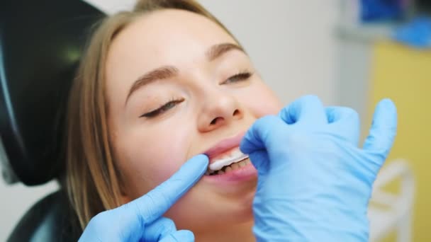 Zubař aplikuje po bělení na zuby připomínající gel. Doktor se stará o pacientovy zuby po bělení na zubní klinice - Záběry, video