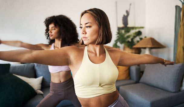 Stretching, fitness en meisje vrienden doen yoga oefening in de woonkamer voor gezondheid en welzijn. Meditatie, zelfzorg en jonge vrouwen doen pilates samen in de lounge van modern appartement. - Foto, afbeelding