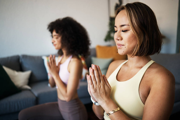 Vrouwen, fitness vrienden en meditatie met namaste of gebedshanden, mindfulness, wellness en gemoedsrust thuis. Yoga, spiritueel en kalm in de lounge met genezing en zen, lichaamsbeweging en zelfzorg. - Foto, afbeelding