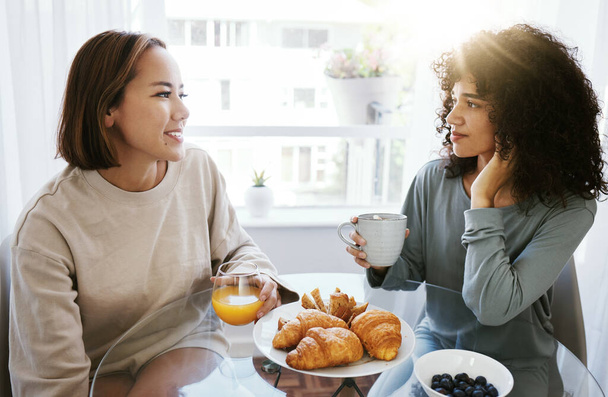 Sinaasappelsap, koffie en gelukkig lesbisch stel thuis aan tafel. Drink, eten en croissant van homoseksuele vrouwen in de ochtend voor ontbijt dieet, eten en gezonde interraciale relatie. - Foto, afbeelding