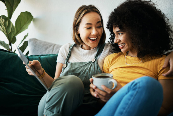 Couple, sofa and women relax with tablet and coffee for social media, internet and watching videos. Love, lgbtq and happy people in living room for bonding, relationship and streaming movies online. - Photo, Image