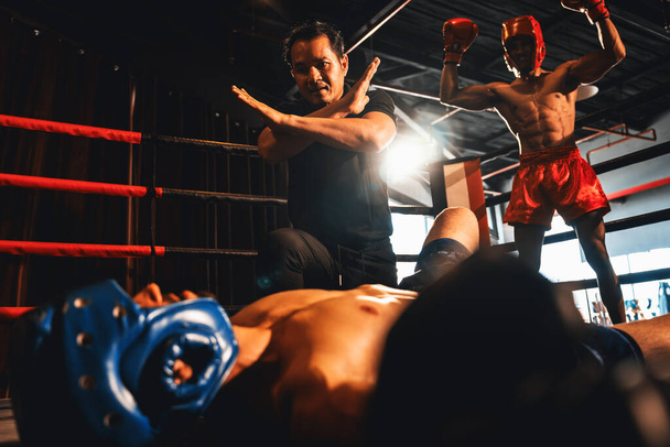 Boxing referee intervene, halting the fight to check fallen competitor after knock out. Referee pauses the action for boxer fighters safety after KO with winner posing in background. Impetus - Photo, Image