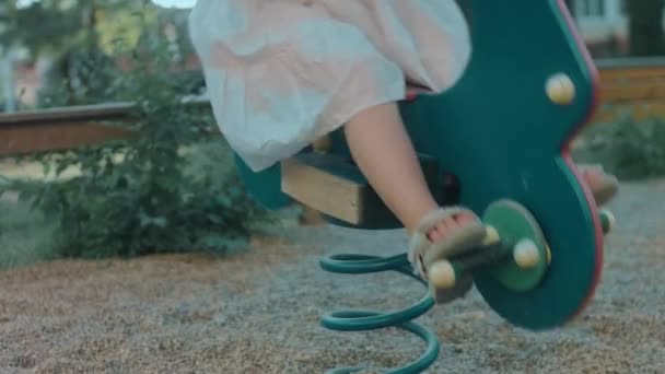 ロッキング馬の遊び場で楽しんでいる小さな幼稚園の少女. 幼稚園のコンセプト, 赤ちゃんの発達と早期 - 映像、動画