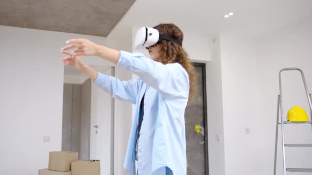 Młoda, nowoczesna, kaukaska kobieta nosząca słuchawki VR z wykorzystaniem technologii rozszerzonej rzeczywistości do przeprojektowania mieszkania - Materiał filmowy, wideo