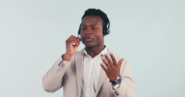 Call center, ügyfélszolgálat és fekete férfi a stúdióban beszél, segít és online tanácsadás. Telemarketing, beszélgetés és személy CRM üzleti, támogatás és kommunikáció szürke háttér. - Felvétel, videó