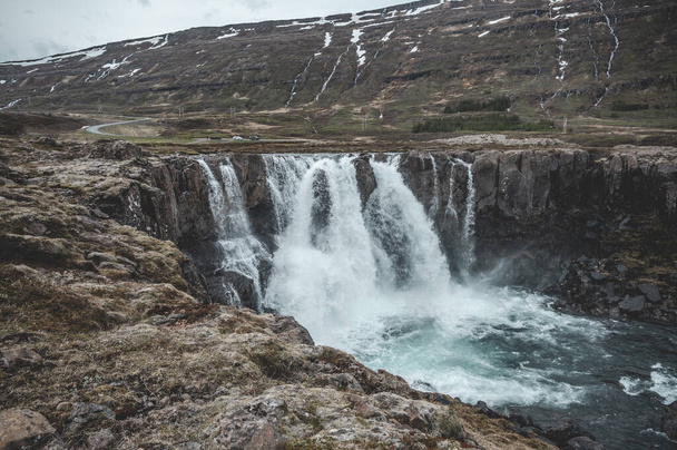 Gyönyörű vízesés Seydisfjordur, Izland hóhegyek a háttérben - Fotó, kép