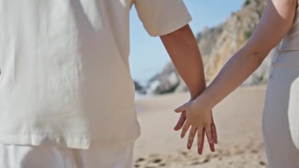 Romantic pair connecting fingers walking tropical ocean coast closeup. Unknown couple enjoying pregnancy spending summer vacation on beach. Pregnant family holding hands relaxing on sandy seashore - Footage, Video
