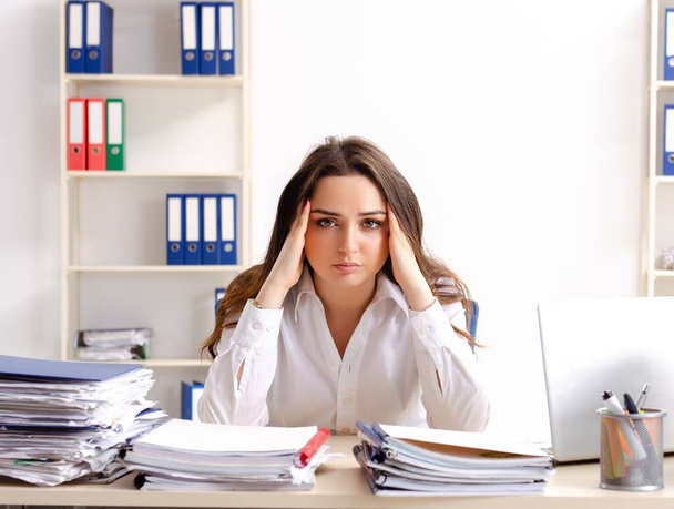 The young female employee unhappy with excessive work - Foto, Imagen