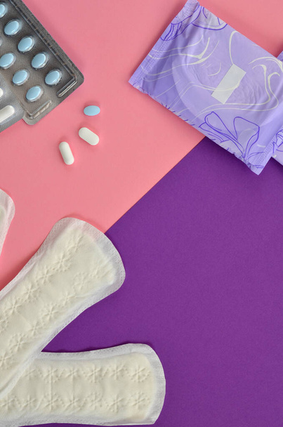 almohadillas y píldoras menstruales y diarias sobre un fondo rosa y púrpura - Foto, imagen