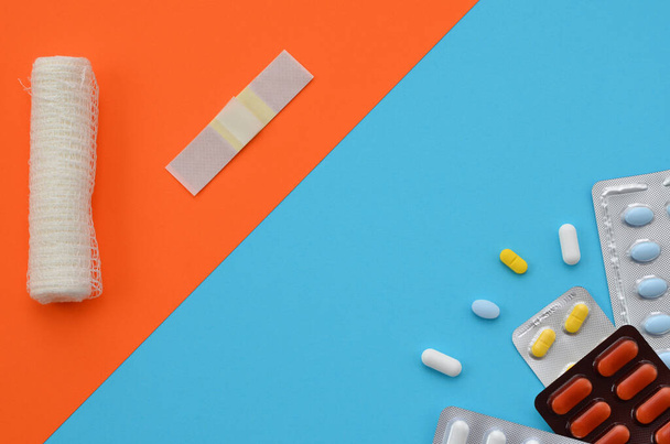 pillole, medicazione bendaggio e gesso su uno sfondo arancione-blu - Foto, immagini