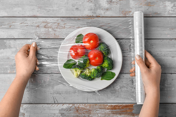 Naisten kädet kääre levy vihanneksia venyttää kääri harmaa puinen tausta - Valokuva, kuva