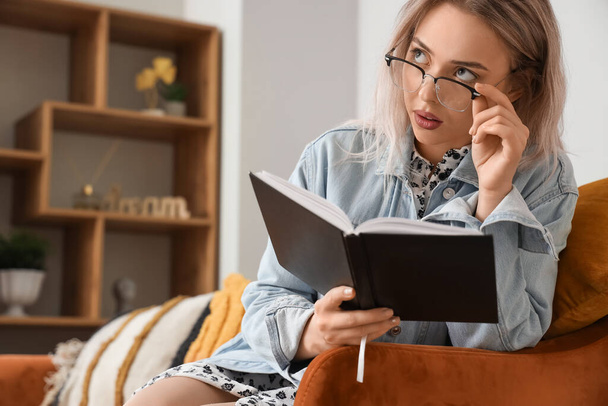 Jovem mulher em óculos elegantes livro de leitura em casa, close-up - Foto, Imagem