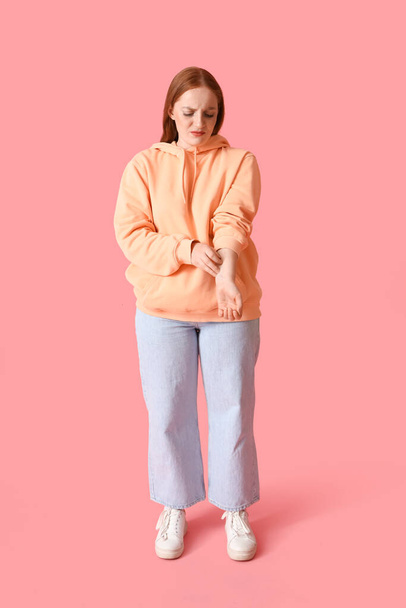 Аллергия молодая женщина царапается на розовом фоне - Фото, изображение