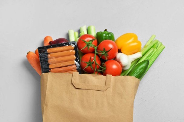 Бумажный пакет с различными продуктами на сером фоне - Фото, изображение