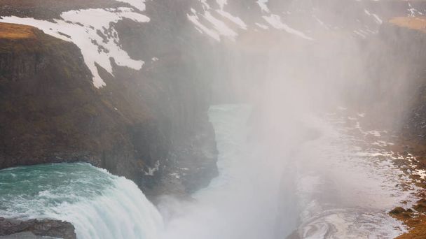 Wodospad Gullfoss w Reykjaviku około marca 2023 roku ze spektakularnym przepływem wody i icelandyjskimi krajobrazami. Majestatyczny strumień rzeczny kaskady w pobliżu zamarzniętych śnieżnych klifów i pól, widok panoramiczny. - Zdjęcie, obraz