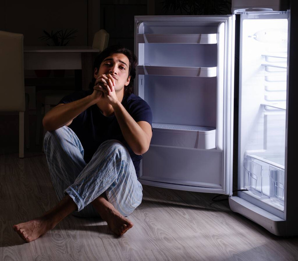 冷蔵庫の近くで夜の食事を壊す男 - 写真・画像