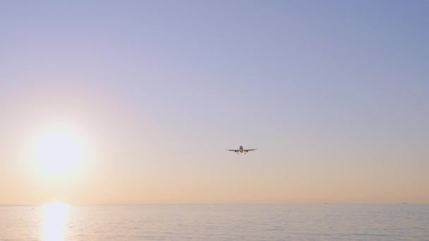 Landingsvliegtuig tegen de achtergrond van kleurrijke blauwe zonsondergang hemel met zon. Landschap met vliegende vliegtuigen in de blauwe lucht met oranje. Achtergrond van het reizen op passagiersvliegtuig Commercieel Vliegtuig Particuliere Jet - Video