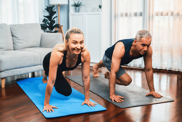 Αθλητικό και ενεργό ηλικιωμένο ζευγάρι κάνει άσκηση σε fit mat με σανίδα αναρρίχησης μαζί στο σπίτι άσκηση ως έννοια της υγιούς fit τρόπο ζωής του σώματος μετά τη συνταξιοδότηση. Μύγα - Φωτογραφία, εικόνα