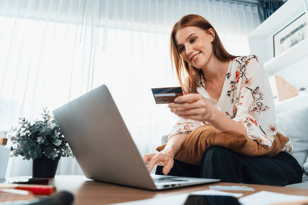 Młoda szczęśliwa kobieta kupuje produkt przez zakupy online w domu podczas zamawiania przedmiotów z Internetu z systemem płatności kartą kredytową online chronionym przez najwyższe cyberbezpieczeństwo z platformy sklepu internetowego - Zdjęcie, obraz