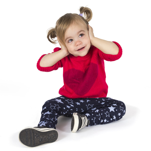 Bebê menina sentado e cobre os ouvidos com as mãos
 - Foto, Imagem