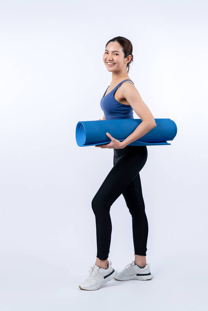 Jonge aantrekkelijke Aziatische vrouw portret in sportkleding met trainingsmat. Gezonde lichaamsbeweging en workout routine levensstijl concept. Studio schot geïsoleerde achtergrond. Krachtig - Foto, afbeelding