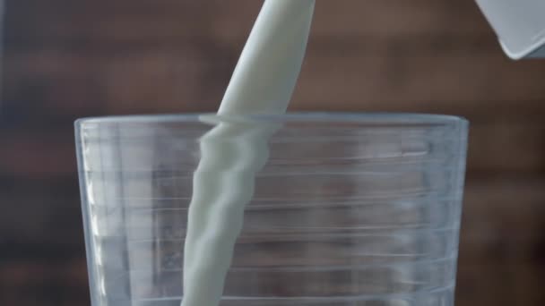 latte fresco bianco viene versato in un bicchiere trasparente . - Filmati, video