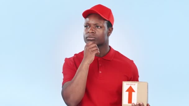 Delivery, box and thinking with a black man courier in studio on a blue background for shipping or distribution. Retail, ecommerce and supply chain logistics with a young person carrying a package. - Footage, Video