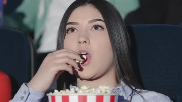 Aziatisch meisje met een emmer popcorn in de bioscoop. Vrienden in de bioscoop een film bekijkt. Bioscoop-, ontspannings- en mensen concept - happy vrienden kijken naar film in het theater. Paar en andere mensen - Video
