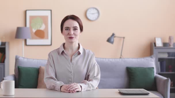 Taille omhoog POV van jonge Kaukasische vrouw zittend aan bureau in het thuiskantoor sprekend op camera over zakelijk onderwerp - Video