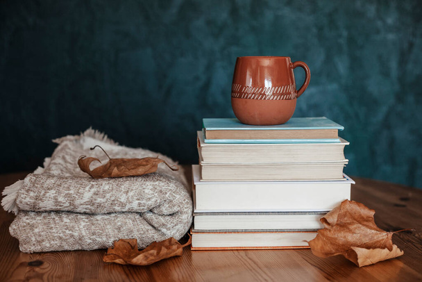 Composición con una pila de libros, bebida caliente en la taza y manta caliente. Acogedora escena de lectura para clima frío con taza de café - Foto, Imagen