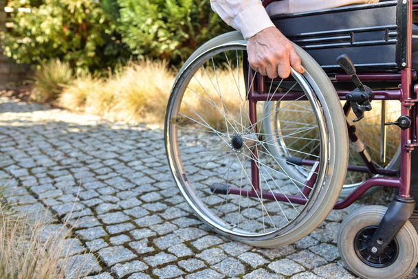 Close-up van mannenhand op wiel van rolstoel  - Foto, afbeelding