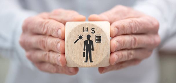 Hand die een houten kubus vasthoudt met symbool voor financieel controleconcept - Foto, afbeelding