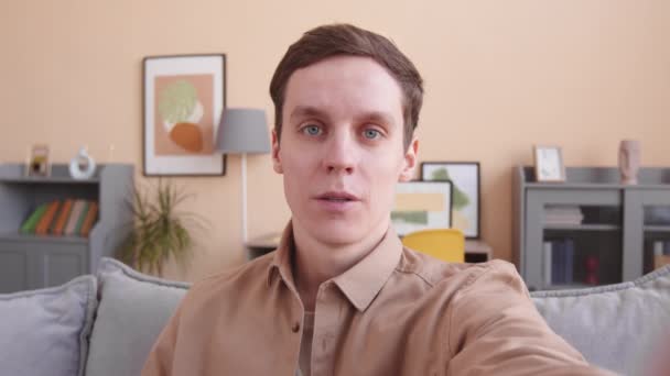 カメラで話す自宅でビデオブログを録画する若い白人男性のハンドヘルドPOVショット - 映像、動画